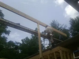 Carpenter setting a ridge beam over a new addition frame — Ice Dam Removal by Roofing Brothers in Doerun