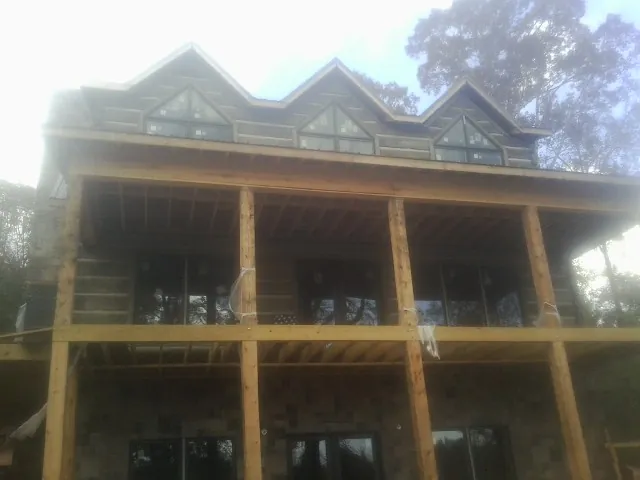 Dormers and porch framing on a large log home under construction — Roof Coating work by our crew in Doerun