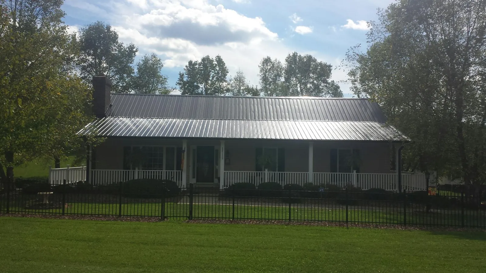Gray metal roof on a brick ranch with a full width front porch — Gutter Guard Installation work by our crew in Doerun
